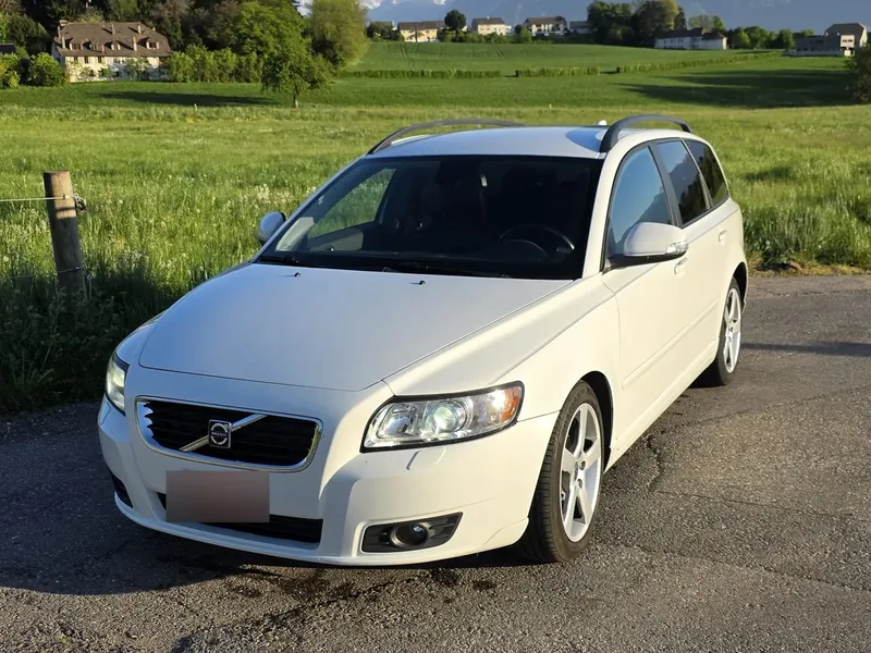 Break Volvo V50 blanc devant un pré et les Alpes