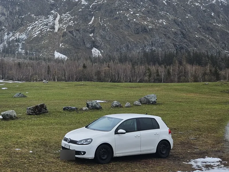 Volkswagen Golf blanche devant une montagne enneigée